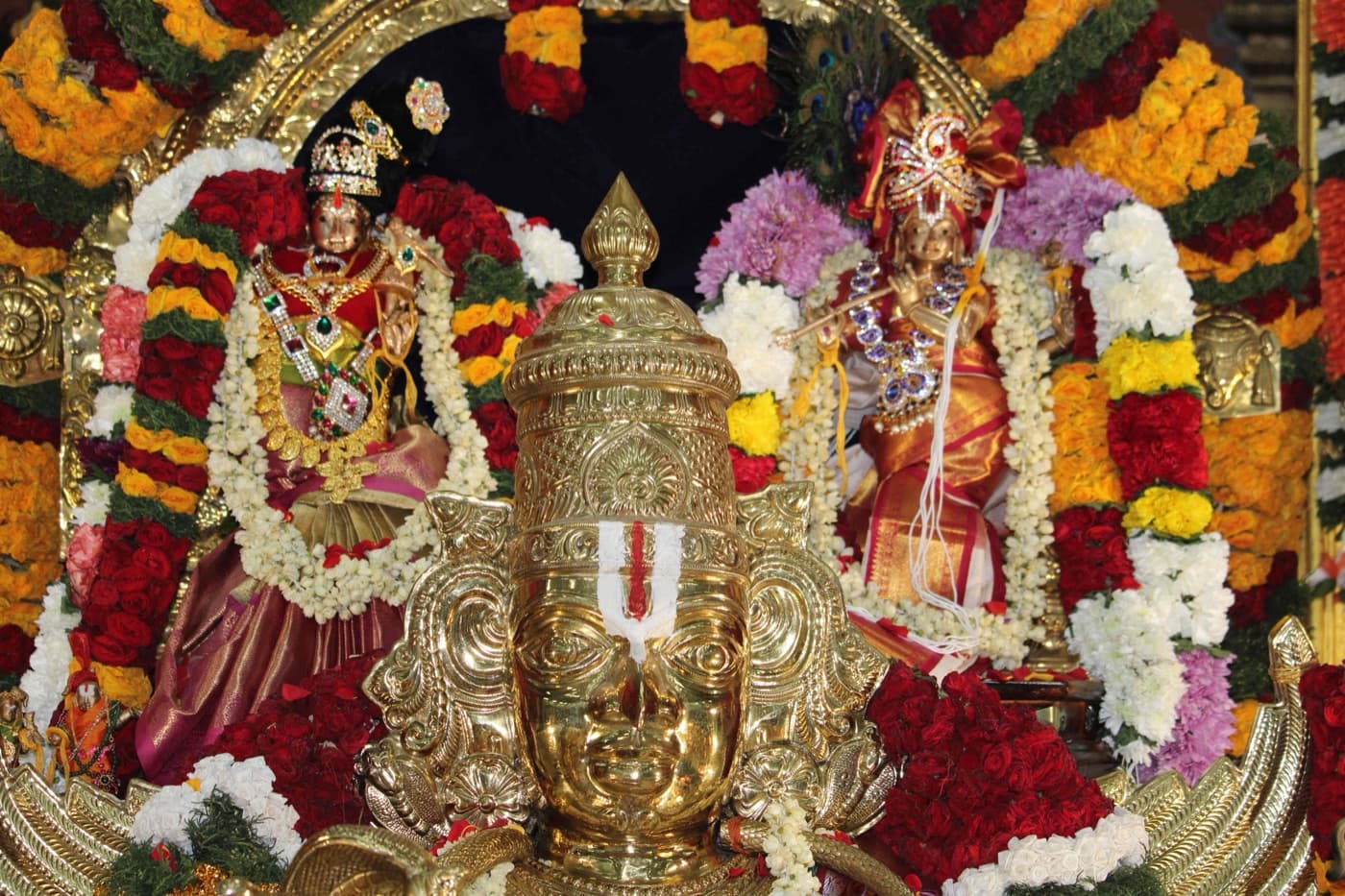 The a:sramam deities garlanded with fresh flowers, ready for darshan