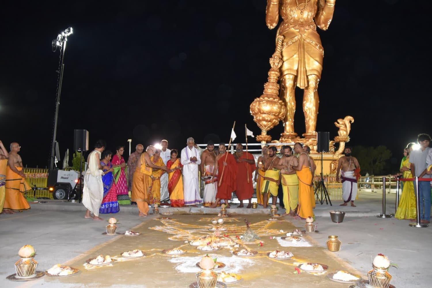 Priests performing an evening ceremony before the illuminated golden Hanuman statue